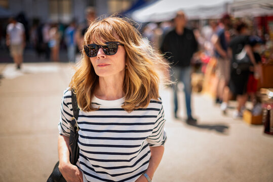 Stylish midlife woman browsing items at outdoor flea market on a sunny day