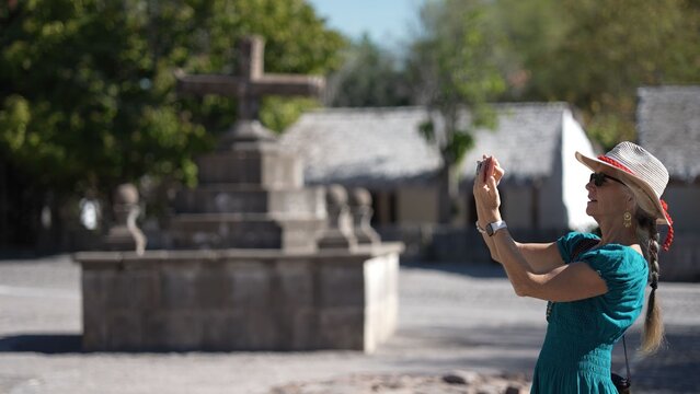 Senior woman enjoys exploring San Javier Mission in Baja California Sur, Mexico at sunrise while capturing moments with her camera