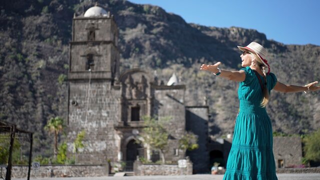 Happy senior woman enjoys exploring San Javier Mission near Loreto at sunrise, experiencing the history of this desert oasis