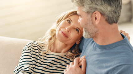 Fototapeta premium Smiling Middle Aged, Caucasian, Enjoying Each Other's Company While Sitting Together On Couch At Home, Feeling Happy And Connected. Family Relationship Concept