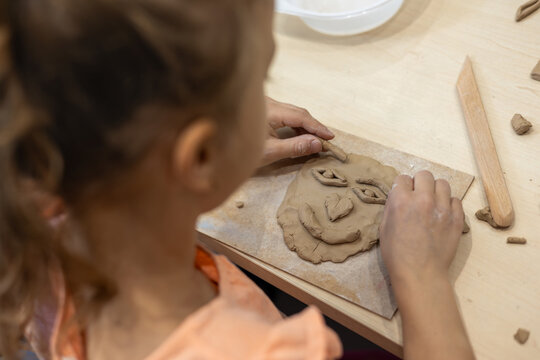 Girl creating clay face during art therapy. Art therapy, emotional expression, emotional development, self-esteem building, stress relief, resilience, child wellbeing and developmental support concept