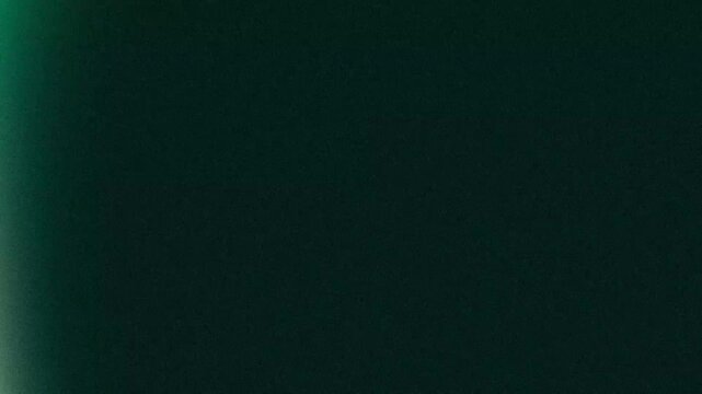 Cinematic Emerald Green Light Leak Glowing on Dark Textured Filmic Background with Moody Vintage Grainy Aesthetic