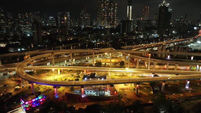 A stunning aerial night view of Atal Setu (Mumbai Trans Harbour Link), showcasing the intricate network of illuminated flyovers and highways glowing in golden light.