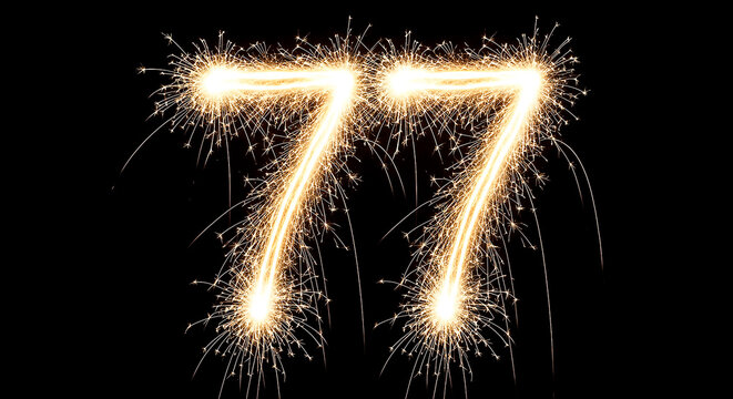 Vibrant sparklers arranged in the shape of the number 77, glowing brightly against a dark background for a festive celebration effect.