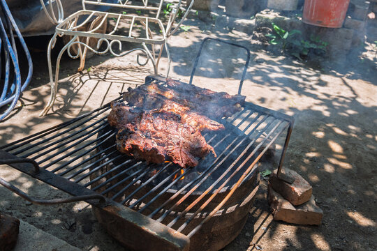 Costillas de carne vacuna cocin&aacute;ndose lentamente sobre parrilla durante proceso de asado argentino