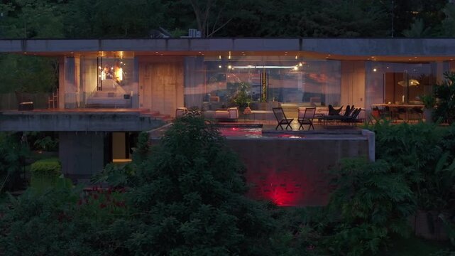 A father and son are relishing in quality time spent together in their exquisite modern house, which boasts a breathtaking swimming pool, all surrounded by vibrant and lush greenery