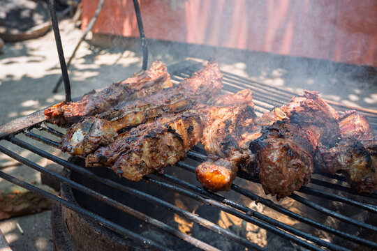 Costillas de carne vacuna cocin&aacute;ndose lentamente sobre parrilla durante proceso de asado argentino