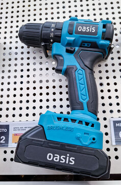 Voronezh, Russia - April 8, 2026.Modern Oasis brushless cordless drill on perforated metal shelf in hardware store located in Russia
