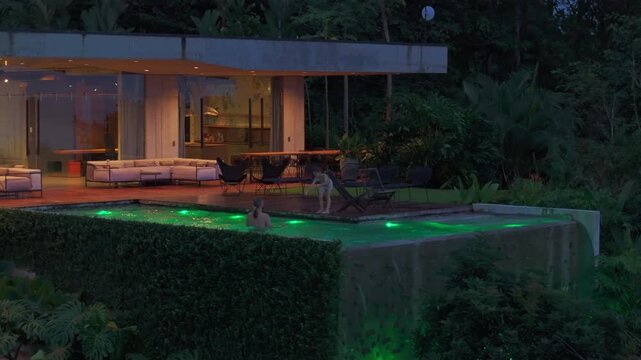On a tranquil and serene evening in a beautiful Costa Rica home, one can see a stunning pool surrounded by lush, vibrant greenery, where a father and son cherish quality time spent together