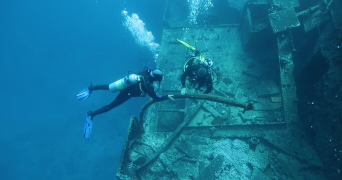 Divers explore the wreck of the SS Thistlegorm. Top diving wreck dives. Swimming over motorbikes and other cargo in hold of Thistlegorm shipwreck in the Red Sea, Sharm el Sheikh, Egypt.
