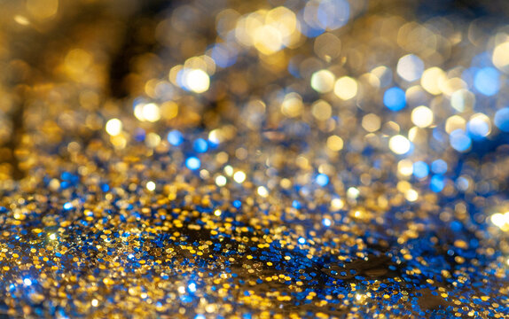 Shimmering blue and gold glitter scattered on a smooth surface