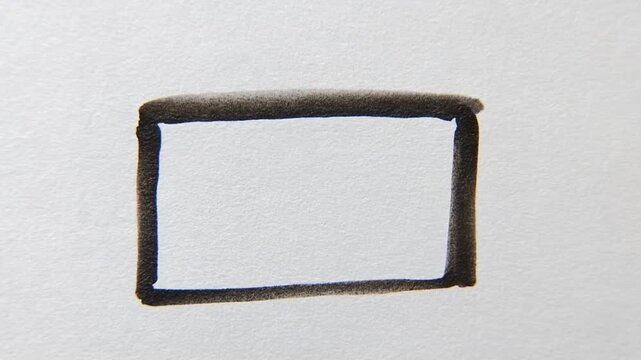 Tracking shot close up of marker pen drawing rectangular outline on paper surface with slight handheld pan in indoor studio
