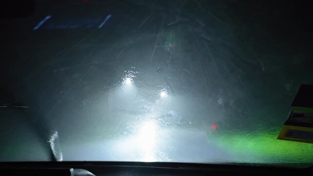 Night road in heavy rain captured from inside a vehicle.