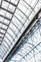 Fototapeta premium Modern Glass Atrium Ceiling With Steel Framework, Skylight Panels and Exposed Ductwork in Commercial Building