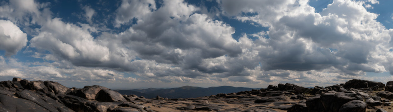Wide Panoramic View of a Rugged Rocky Mountain Range Top with Dramatic Cumulus and Stratocumulus Clouds