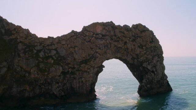 Aerial drone shot pulling back to reveal the iconic Durdle Door natural arch in Dorset, England
