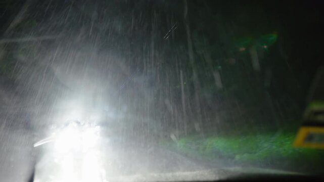 Dramatic POV footage driving through intense nighttime rainstorm on dark rural road.