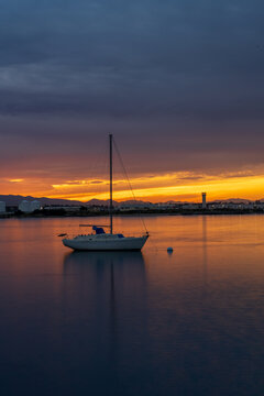 White Sailboat Anchored on Calm Water at Sunset