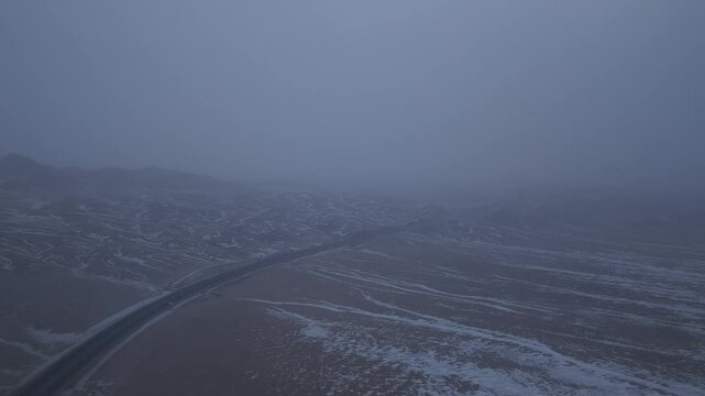 Aerial view of winter highway and snow patterned hills in Xinjiang