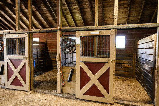 Horse stall in stable barn with red and tan door