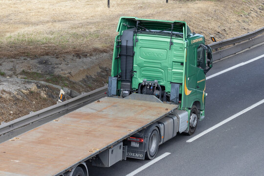 Green volvo truck hauling empty flatbed trailer on highway