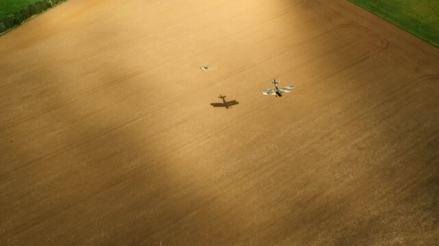 Aerial view of a vintage biplane flying low over agricultural fields in the countryside
