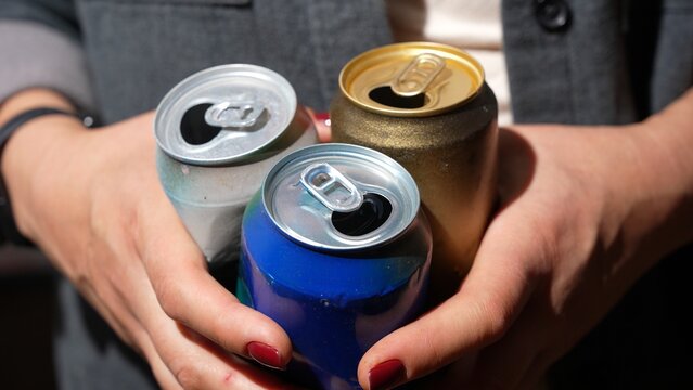 Woman with empty drink cans showing consumption waste