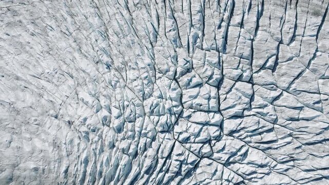 Aerial drone view of glacier cracks and ice surface texture. Abstract frozen nature background with crevasses and arctic pattern from above.