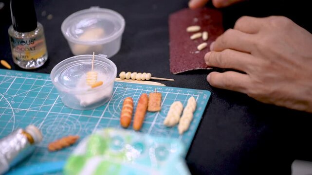 Artisan sculpting miniature clay vegetables at craft workshop