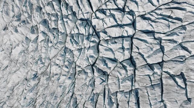 Aerial drone view of glacier cracks and ice surface texture. Abstract frozen nature background with crevasses and arctic pattern from above.