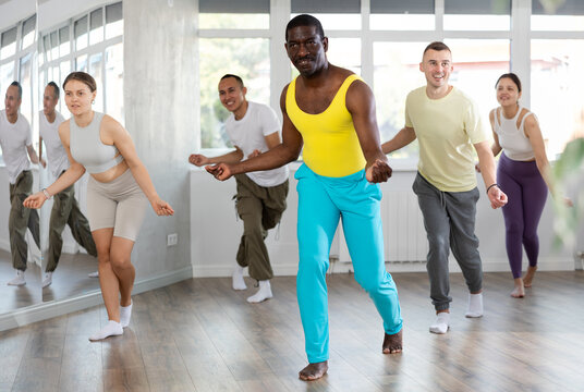 Active middle-aged Afro-American man practicing hip-hop dance in training hall during dancing classes