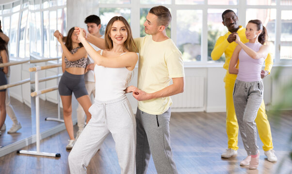 Graceful young girl and boy training waltz dance poses in dancehall during workout session