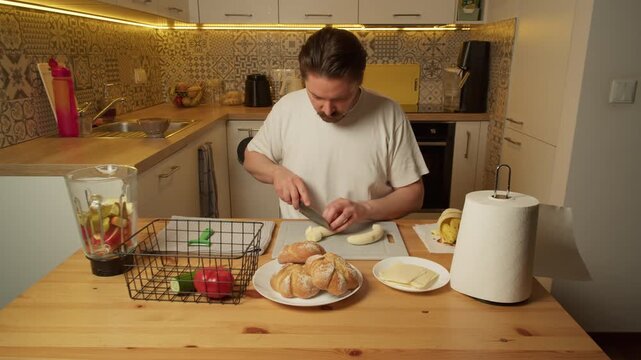 Man slicing banana on cutting board in rustic kitchen morning