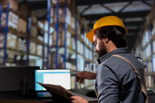 Industrial employee reviewing cargo shipment details files, working on quality control and logistics in storage room. Depot supervisor ensuring easy distribution for supply chain management.