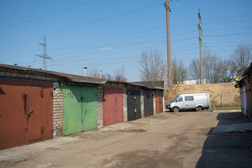 Fototapeta premium Row of garages with a driveway and a white van in the distance, urban storage area, outdoor parking and transport concept, neighborhood infrastructure, copy space.