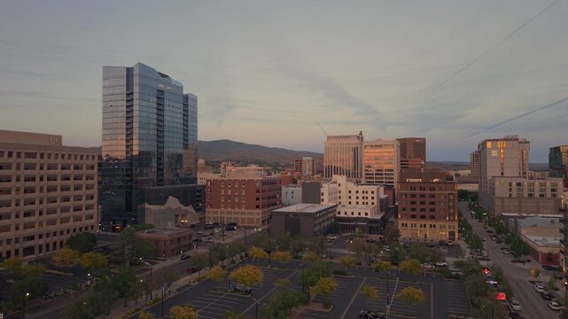 Slow moving push-in drone shot of downtown Boise Idaho., taken from 11th Ave., at sunset. The iconic Arthur Building stands out against the warm sunset sky over the glowing city. 