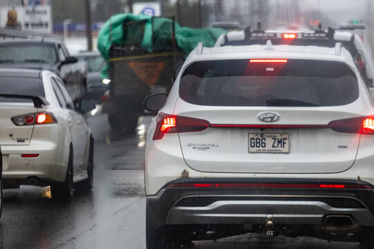 La Tuque, Canada, 07 May 2026 : White Hyundai Santa Fe SUV and Mitsubishi Lancer car are stopped in slow-moving traffic on a wet road.