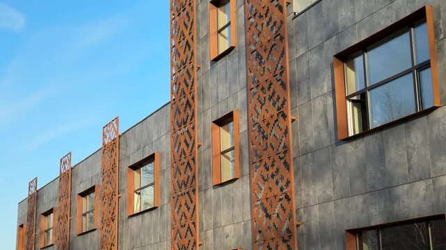 Industrial building with rusted cladding bathed in warm late afternoon sunlight, concrete panels marked by weathered bolts