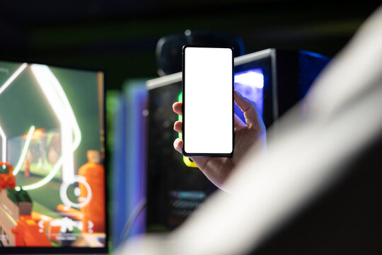Player looking at mockup mobile phone while playing SF videogame, using gaming computer peripherals. Gamer holding isolated screen smartphone, fighting enemies with futuristic gun, close up