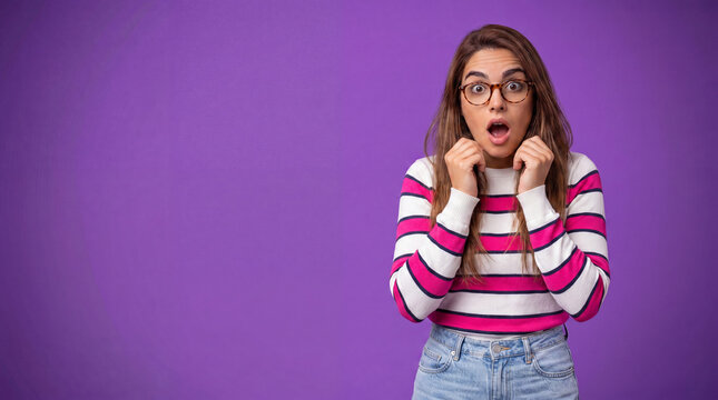 A young woman with glasses and a striped sweater looks shocked, her mouth agape and hands by her face, against a vibrant purple background