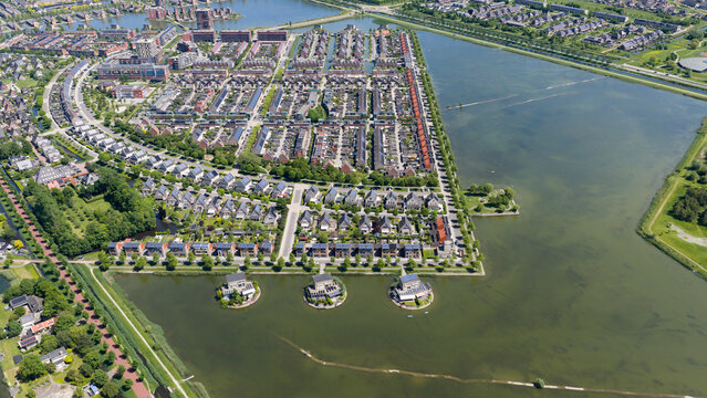 Aerial view of modern residential houses with solar panels and unique floating homes on a lake in the Stad van de Zon district Heerhugowaard, North Holland, Netherlands.