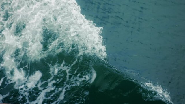 Powerful turquoise ocean waves crash and churn creating white foam and sea spray against deep blue water. Dynamic close up view captures the raw energy and movement of the sea.