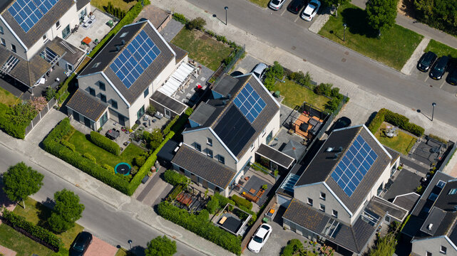 Aerial view of modern residential houses with solar panels on rooftops and green gardens in Heerhugowaard, North Holland, Netherlands.