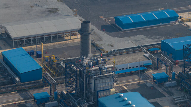 Aerial view of Sriracha Power Plant GSRC with a large chimney stack and blue industrial buildings in Tambon Khao Khan Song, Chang Wat Chon Buri, Thailand.