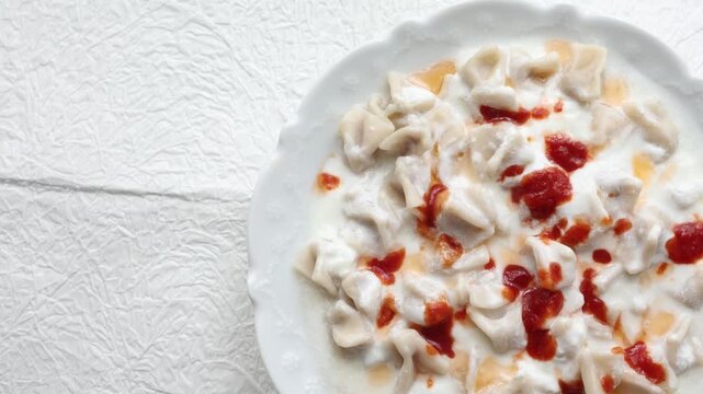 Close-up of traditional Turkish manti dumplings served with garlic yogurt and spicy butter sauce