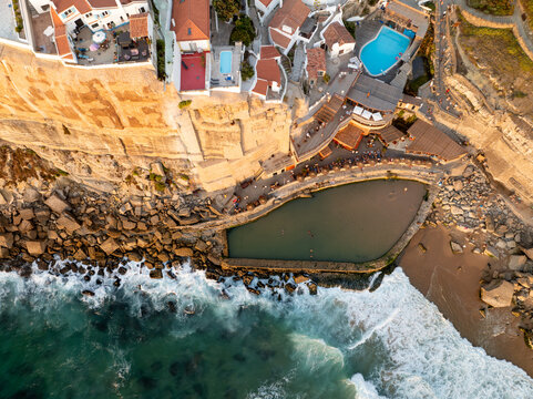Aerial view of the coastal village of Praia das Azenhas do Mar with its natural rock pool and white houses perched on cliffs in Colares, Lisbon, Portugal.