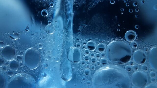 Macro slow motion close up of bubbles rising and forming in water inside glass vessel in studio setting