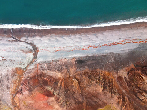 Aerial view of the colorful volcanic cliffs and dark sand beach of Brunavik bay with turquoise sea water Bakkagerdi, Mulathing, Iceland.
