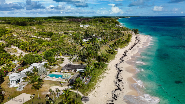 Aerial view of North Palmetto Point Beach with turquoise ocean waves, white sand, and luxury villas with a swimming pool North Palmetto Point, Central Eleuthera, The Bahamas.