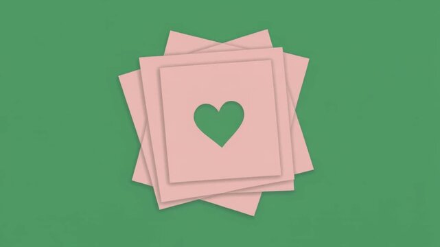 A stack of pink square paper notes with a heart cutout isolated on a solid green screen chroma key background. Romantic theme video for Valentine's Day.